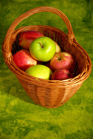 Fresh apple mix in basket on green backgroundの写真素材