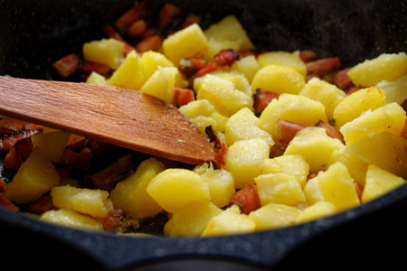Cooking sliced potatoes with bacon on frying panの写真素材