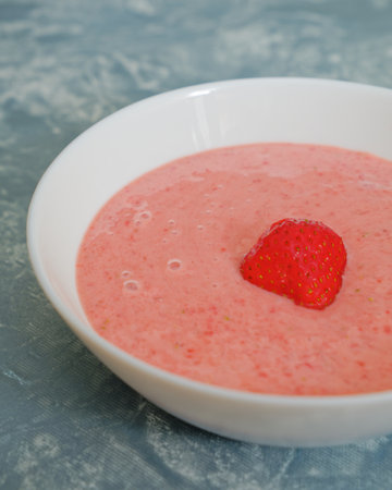 Tasty fresh summer strawberry soup in bowl on blue backgroundの写真素材