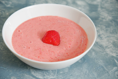 Tasty fresh summer strawberry soup in bowl on blue backgroundの写真素材