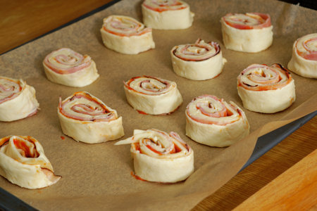 Puff pastry pizza rolls preparation on baking trayの写真素材