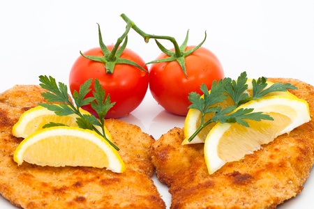 Detail of schnitzel with lemons and tomatoes, isolated on white background.の写真素材
