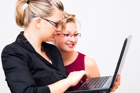 Two young business women with laptop, isolated on white background.の写真素材