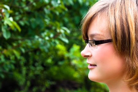 Beautiful young woman face with eyeglasses over natural green background.の写真素材