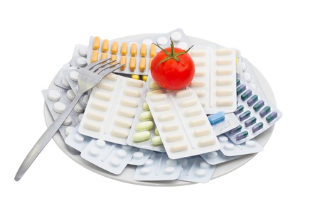 Pills and tablets with tomato on plate, isolated on white background.の写真素材