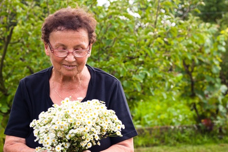 Senior woman with flowers in the garden.の写真素材