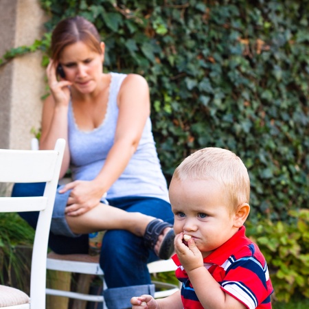 Young woman on the phone and a little boy outdoors.の写真素材