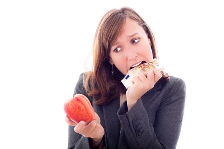 European crisis concept. Desperate woman with apple, eating Euro bank note, isolated on white background.の写真素材