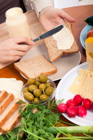 Detail of kitchen table and female hands spreading mayonnaise on sandwiches.の写真素材