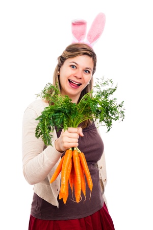 Funny happy laughing woman with bunny ears holding fresh carrots, isolated on white background.の写真素材