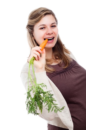 Young beautiful woman eating fresh carrot, isolated on white background.の写真素材