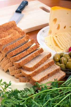 Detail of kitchen table with bread, Emmenthal cheese, vegetable a chopping board.の写真素材