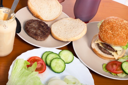 Detail of table with served homemade double hamburgers with cheese and vegetable.の写真素材