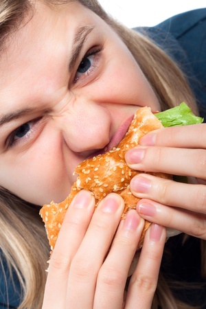 Close up of young hungry woman eating hamburger.の写真素材