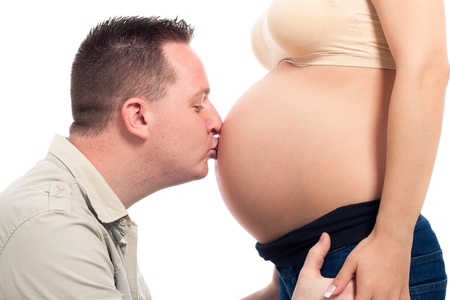 Happy husband kissing pregnant woman belly, isolated on white background.の写真素材