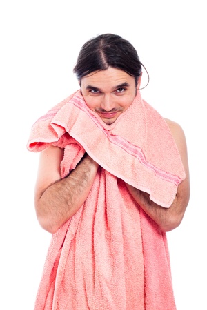 Young happy handsome man after bath using peach towel, isolated on white background.の写真素材