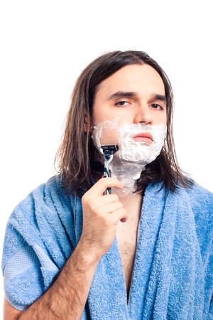 Young longhaired man shaving after bath, isolated on white background.の写真素材