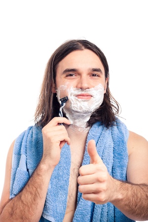 Young longhaired happy man shaving after bath, isolated on white background.の写真素材