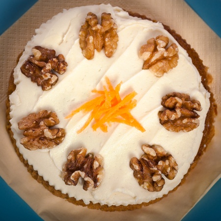 Close up of delicious whole carrot cake with icing, grated carrots and walnuts.の写真素材