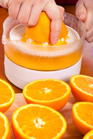 Close up of squeezing fresh oranges and preparing fresh homemade orange juice.の写真素材