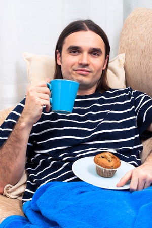 Young man having breakfast and relaxing on sofa.の写真素材