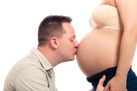 Expectant father kissing pregnant woman belly, isolated on white background.の写真素材