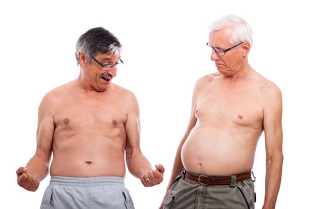 Two happy naked senior men comparing body shape, isolated on white background.の写真素材