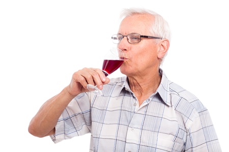Senior man drinking glass of red wine, isolated on white background.の写真素材