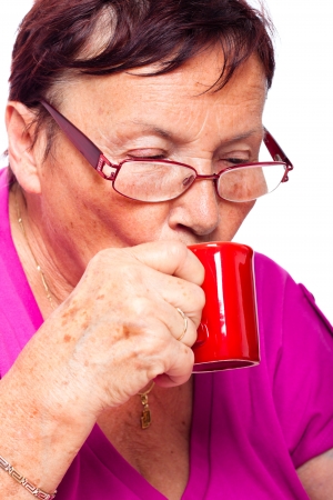 Close up of senior woman drinking espresso, isolated on white background.の写真素材
