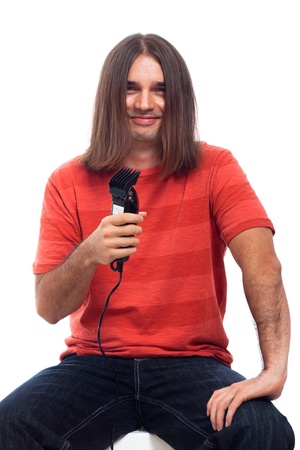Happy smiling long haired young man holding hair trimmer, isolated on white background.の写真素材