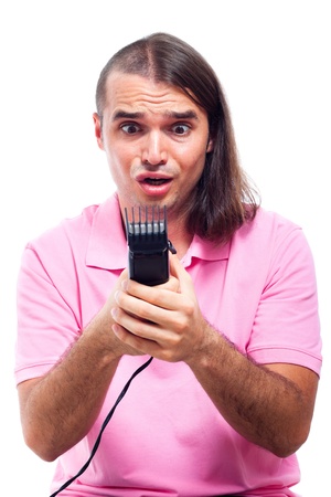 Unhappy shocked half bald young man holding hair trimmer, isolated on white background.の写真素材