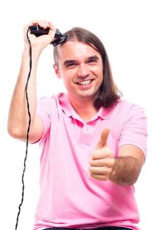 Happy young man shaving his head with hair trimmer, isolated on white background.の写真素材