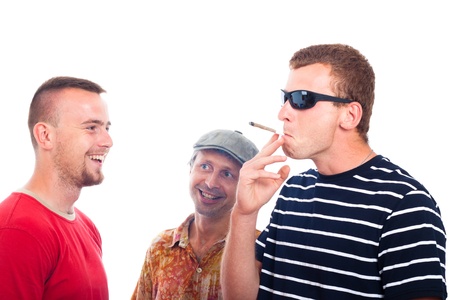 Three young smiling guys smoking hashish joint, isolated on white background.の写真素材