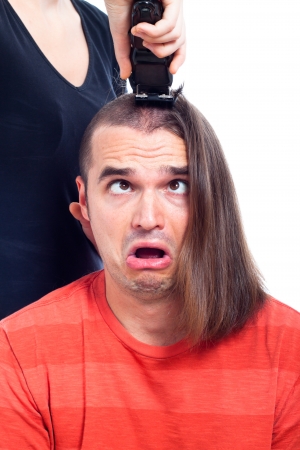 Close up of shocked long haired man being shaved with hair trimmer, isolated on white background.の写真素材