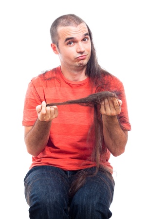 Funny man holding his long shaved hair, isolated on white background.の写真素材