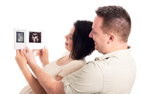 Happy pregnant couple looking at ultrasound pictures of baby, isolated on white background.