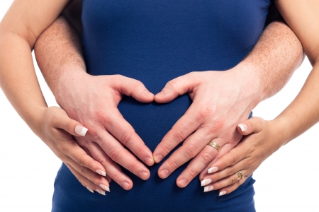 Detail of pregnant couple hands and belly, isolated on white background.の写真素材