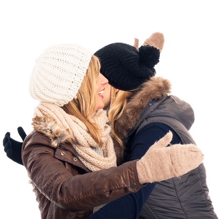 Two young happy friends in winter clothes greeting and hugging, isolated on white background.の写真素材