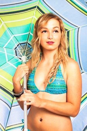 Portrait of young attractive blond woman in blue bikini holding parasol.の写真素材