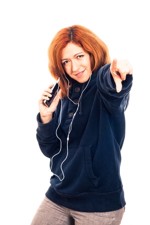 Young happy woman in blue hoodie holding smartphone, listening music and pointing at you, isolated on white background.の写真素材