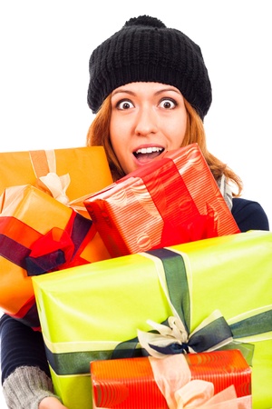 Ecstatic happy woman in winter hat holding many colorful gift boxes, isolated on white background.の写真素材