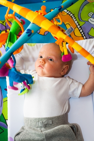 Cute little baby boy lying in bed with toys.の写真素材