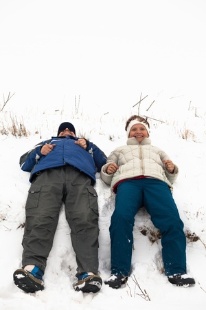 Happy middle aged couple relaxing on snow during winter vacation.の写真素材