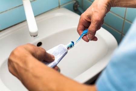 Close up of male hands with toothbrush and toothpaste in bathroom.の写真素材