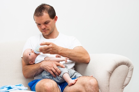 Portrait of a man feeding cute baby boy.の写真素材