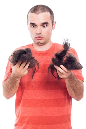 Shocked bald man holding his long shaved hair, isolated on white backgroundの写真素材