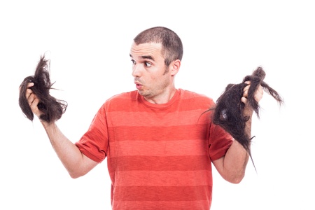 Surprised bald man holding his long shaved hair, isolated on white backgroundの写真素材