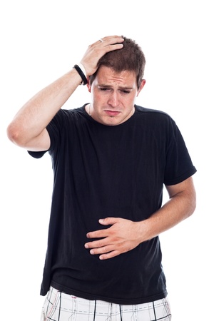 Young unhappy man touching his belly and head, isolated on white backgroundの写真素材