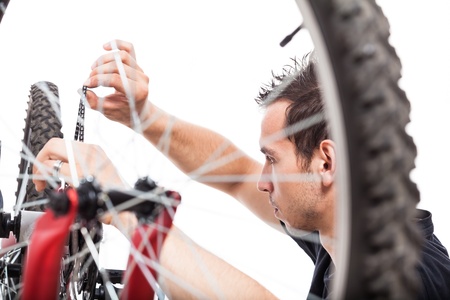 Young man adjusting bike chain and repairing bicycle, isolated on white backgroundの写真素材