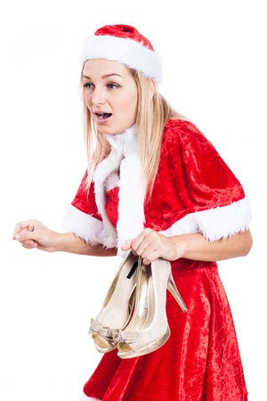 Shocked woman in Christmas costume holding high heel shoes, isolated on white background.の写真素材